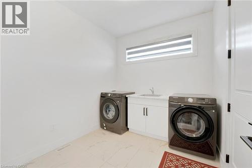Laundry area with cabinet space, light marble finish floors, and separate washer and dryer - 7266 Silver Creek Circle, London, ON - Indoor Photo Showing Laundry Room