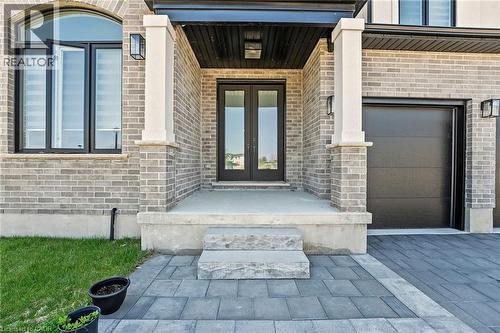 Property entrance featuring french doors, brick siding, covered porch, and a garage - 7266 Silver Creek Circle, London, ON - Outdoor