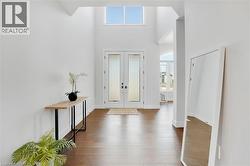 Entrance foyer with healthy amount of natural light, french doors, a high ceiling, and dark wood-type flooring - 