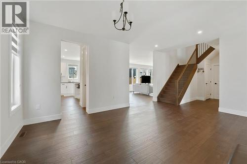 Unfurnished living room featuring stairs, recessed lighting, dark wood-type flooring, and a chandelier - 7266 Silver Creek Circle, London, ON - Indoor