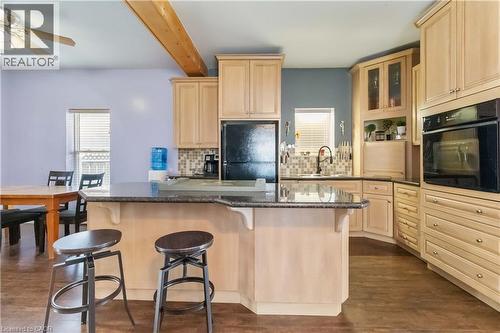 Kitchen featuring light brown cabinets, a kitchen bar, black appliances, glass insert cabinets, and dark wood-style floors - 112 Eagle Avenue, Brantford, ON - Indoor Photo Showing Kitchen
