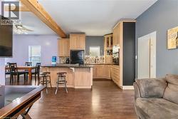 Kitchen with light brown cabinets, glass insert cabinets, a breakfast bar area, dark wood-style flooring, and backsplash - 