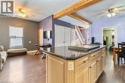 Kitchen featuring a ceiling fan, light brown cabinetry, open floor plan, and a kitchen island - 