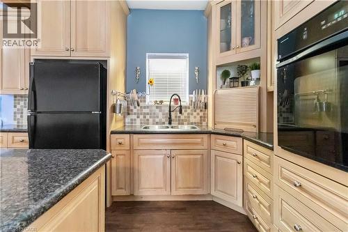 Kitchen featuring black appliances, glass insert cabinets, dark stone countertops, and decorative backsplash - 112 Eagle Avenue, Brantford, ON - Indoor Photo Showing Kitchen With Double Sink