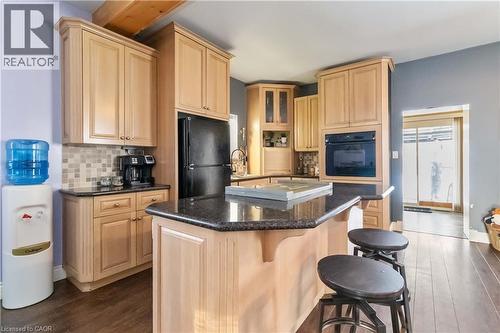 Kitchen featuring light brown cabinets, dark wood-type flooring, a kitchen breakfast bar, a center island, and black appliances - 112 Eagle Avenue, Brantford, ON - Indoor Photo Showing Kitchen