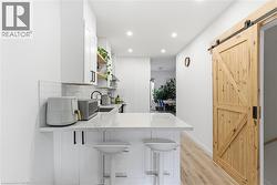 Kitchen with open shelves, light stone countertops, a peninsula, a barn door, and a breakfast bar - 