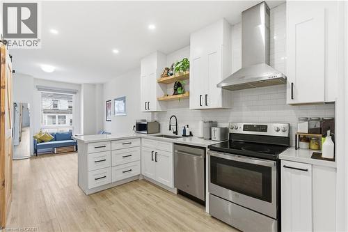 Kitchen featuring stainless steel appliances, open shelves, a peninsula, wall chimney exhaust hood, and white cabinets - 40 Fullerton Avenue, Hamilton, ON - Indoor Photo Showing Kitchen With Stainless Steel Kitchen With Upgraded Kitchen