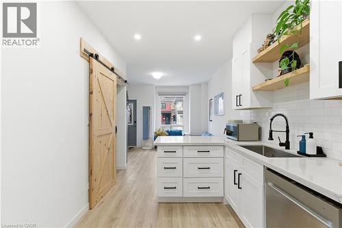 Kitchen featuring open shelves, a barn door, a peninsula, appliances with stainless steel finishes, and light wood finished floors - 40 Fullerton Avenue, Hamilton, ON - Indoor Photo Showing Kitchen With Upgraded Kitchen