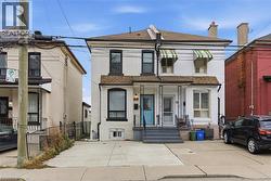 View of front of home with brick siding, a shingled roof, and a chimney - 