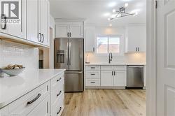 Kitchen with appliances with stainless steel finishes, white cabinetry, light wood-style floors, backsplash, and recessed lighting - 