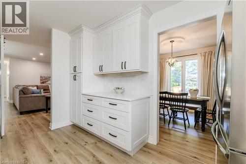 Kitchen with freestanding refrigerator, white cabinetry, light wood finished floors, a chandelier, and light stone counters - 5 Newport Lane, Port Dover, ON - Indoor