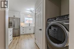 Washroom featuring washer / clothes dryer, light wood-style floors, and a chandelier - 