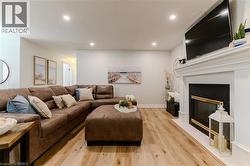 Living area with a glass covered fireplace, light wood-style flooring, and recessed lighting - 