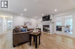 Living area with light wood-style flooring, a glass covered fireplace, french doors, and recessed lighting - 
