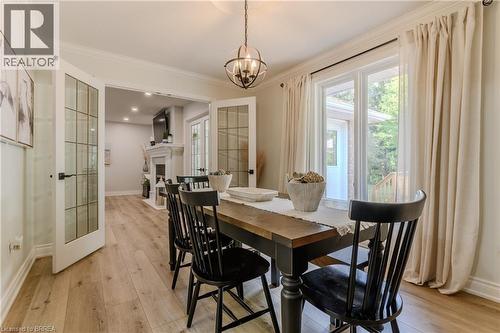 Dining room with french doors, light wood finished floors, ornamental molding, a fireplace, and a chandelier - 5 Newport Lane, Port Dover, ON - Indoor Photo Showing Dining Room