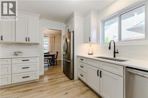 Kitchen featuring stainless steel appliances, white cabinetry, backsplash, light wood-style floors, and light stone counters - 5 Newport Lane, Port Dover, ON - Indoor Photo Showing Kitchen With Upgraded Kitchen