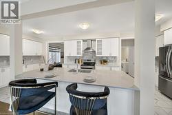 Kitchen with white cabinets, light stone countertops, backsplash, and appliances with stainless steel finishes - 