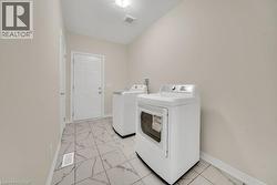 Laundry area featuring light marble finish floors and separate washer and dryer - 