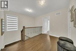Unfurnished room with wood finished floors, an upstairs landing, and a textured ceiling - 