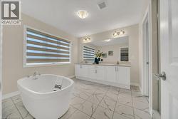 Bathroom with light marble finish flooring, double vanity, and a soaking tub - 