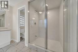Full bathroom featuring a stall shower, vanity, and light marble finish floors - 