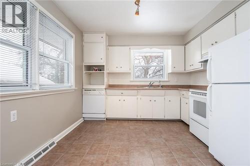 Kitchen with white appliances, decorative backsplash, open shelves, white cabinets, and light tile patterned floors - 120 Fourth Avenue, Kitchener, ON - Indoor Photo Showing Kitchen