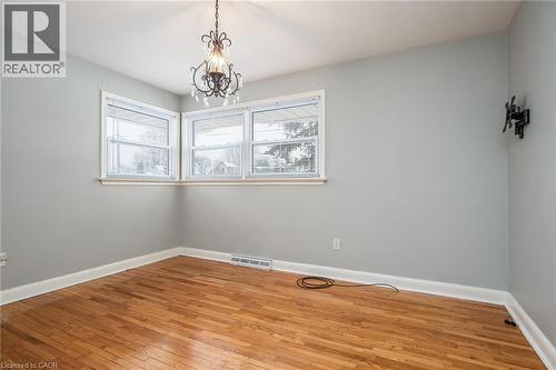 Empty room with light wood-style floors and a chandelier - 120 Fourth Avenue, Kitchener, ON - Indoor Photo Showing Other Room