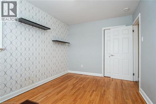 Unfurnished bedroom with light wood-style flooring, an accent wall, and wallpapered walls - 120 Fourth Avenue, Kitchener, ON - Indoor Photo Showing Other Room