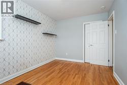 Unfurnished bedroom with light wood-style flooring, an accent wall, and wallpapered walls - 