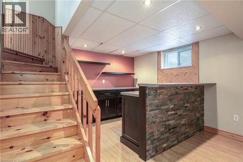 Indoor dry bar featuring stairs, a drop ceiling, dark brown cabinetry, light wood-style flooring, and light countertops - 120 Fourth Avenue, Kitchener, ON - Indoor