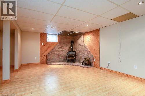 Basement with wooden walls, a wood stove, a paneled ceiling, and light wood finished floors - 120 Fourth Avenue, Kitchener, ON - Indoor Photo Showing Basement