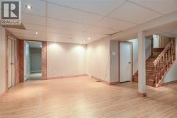 Finished below grade area featuring stairs, a paneled ceiling, light wood finished floors, and recessed lighting - 