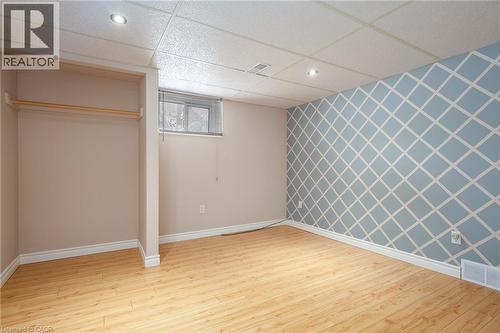 Unfurnished bedroom featuring an accent wall, wallpapered walls, light wood-type flooring, a drop ceiling, and recessed lighting - 120 Fourth Avenue, Kitchener, ON - Indoor Photo Showing Other Room