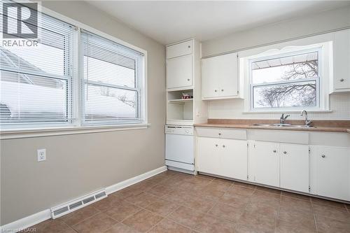 Kitchen featuring white cabinets, white dishwasher, light countertops, open shelves, and light tile patterned floors - 120 Fourth Avenue, Kitchener, ON - Indoor Photo Showing Kitchen With Double Sink
