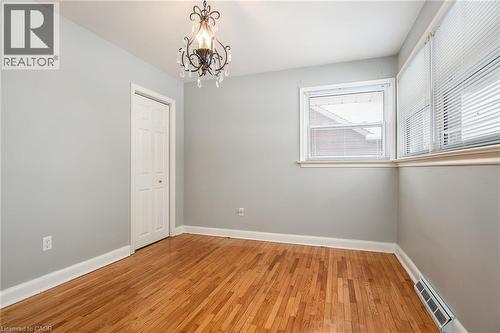 Empty room featuring light wood-style floors and hanging lights - 120 Fourth Avenue, Kitchener, ON - Indoor Photo Showing Other Room