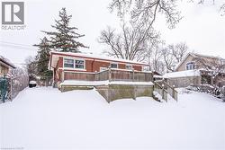 Snow covered back of property featuring a wooden deck and brick siding - 