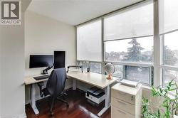 Home office featuring dark wood-style floors and a wall of windows - 