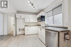 Kitchen featuring stainless steel appliances, white cabinetry, and light wood-style flooring - 