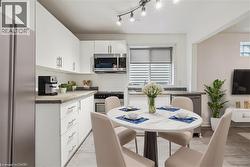 Kitchen with appliances with stainless steel finishes, white cabinetry, and light wood-style flooring - 