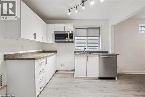 Kitchen featuring appliances with stainless steel finishes, white cabinets, light wood finished floors, and dark countertops - 28 Grove Street, Hamilton, ON - Indoor Photo Showing Kitchen