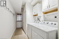 Laundry room with cabinet space, washer and clothes dryer, and light tile patterned floors - 