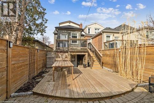 Rear view of house featuring a wooden deck, a fenced backyard, outdoor dining area, and stairway - 28 Grove Street, Hamilton, ON - Outdoor With Deck Patio Veranda