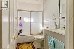 Full bathroom with shower / bath combination with glass door, vanity, and tile walls - 