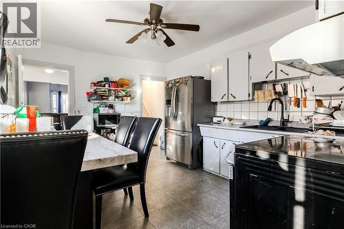Kitchen with stainless steel appliances, white cabinets, extractor fan, decorative backsplash, and light countertops - 126 Tisdale Street N, Hamilton, ON - Indoor
