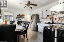Kitchen with stainless steel appliances, white cabinets, extractor fan, decorative backsplash, and light countertops - 