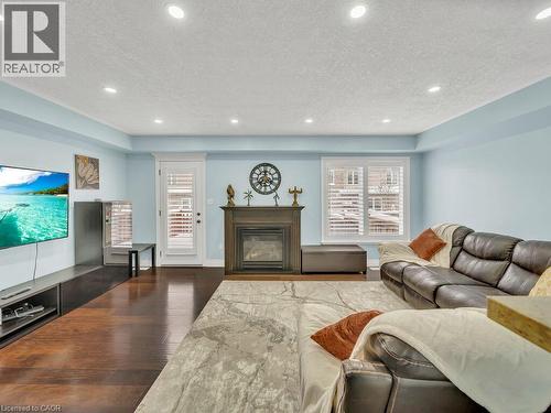 Living area featuring a textured ceiling, a glass covered fireplace, dark wood-type flooring, and recessed lighting - 29 Amsterdam Crescent, Guelph, ON - Indoor Photo Showing Living Room With Fireplace