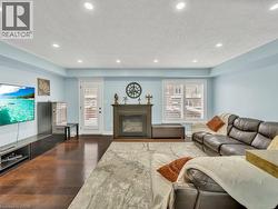 Living area featuring a textured ceiling, a glass covered fireplace, dark wood-type flooring, and recessed lighting - 