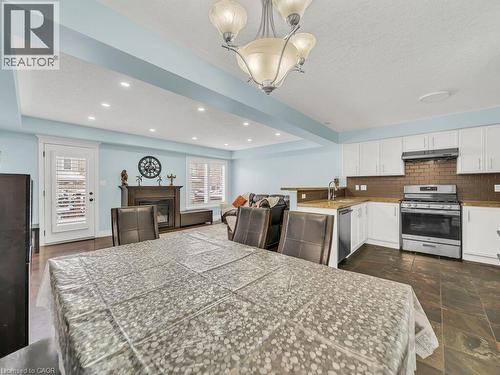Dining room with recessed lighting, a glass covered fireplace, a chandelier, plenty of natural light, and dark stone finish flooring - 29 Amsterdam Crescent, Guelph, ON - Indoor