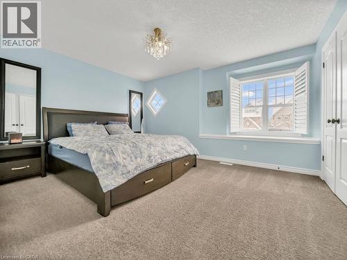 Carpeted bedroom featuring a textured ceiling and a chandelier - 29 Amsterdam Crescent, Guelph, ON - Indoor Photo Showing Bedroom