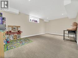 Recreation room with light carpet, a textured ceiling, and recessed lighting - 